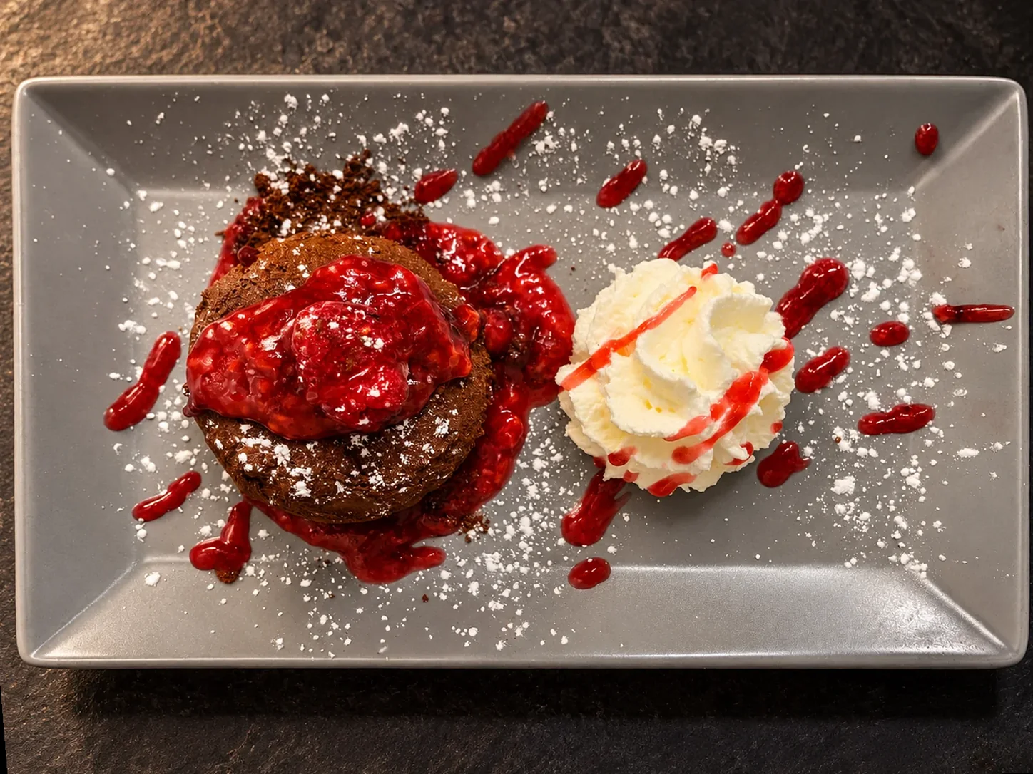 Schokoladensoufflé mit Himbeersauce, Sahne und Puderzucker