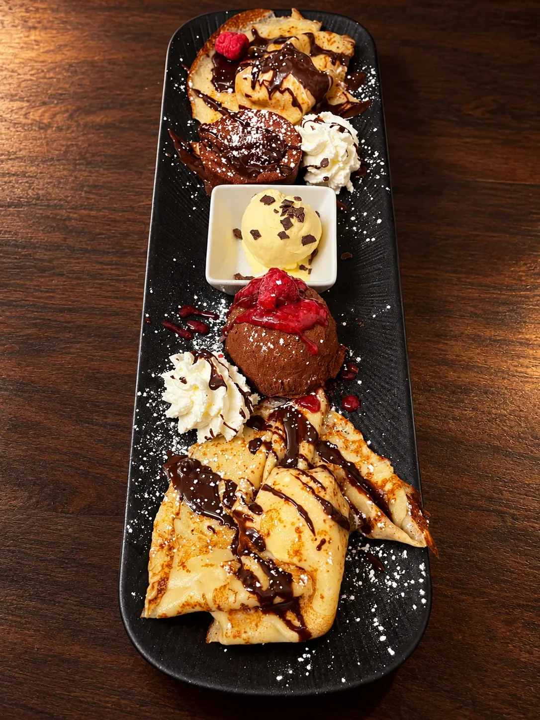 Nachtisch-Variation für zwei: Palatschinken mit Schokosauce, Schokoladenkugel mit Himbeeren, Vanilleeis und Sahne